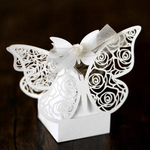 Close-up of white laser-cut butterfly gift box with rose patterns and ribbon on wood