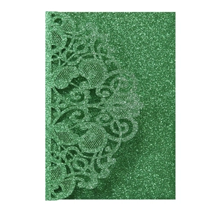 Macro detail of laser-cut lace pattern on green glitter cardstock wedding invitation