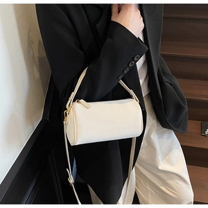 Close-up of a white lychee texture cylindrical crossbody bag with gold-tone hardware detail