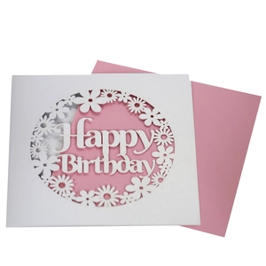 Detail view of laser-cut white Happy Birthday card with floral pattern and pink envelope