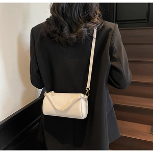 Detail of cream lychee texture on cylindrical crossbody bag with gold hardware