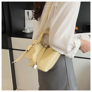 Detail of light yellow crocodile texture mini bucket bag with gold lock and drawstring