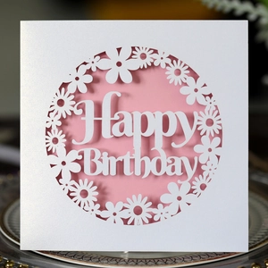 Close-up of laser-cut flower wreath happy birthday card with elegant pink lining