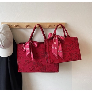 Detail of red jacquard wedding tote bags with silk ribbon bows and traditional symbols