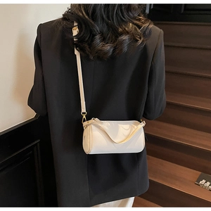 Close-up of a cream-colored cylinder crossbody bag with litchi texture and leather details