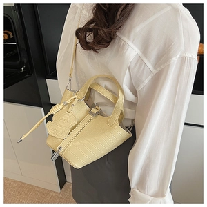 Close-up of cream crocodile pattern mini handbag with handle and bear charm detail