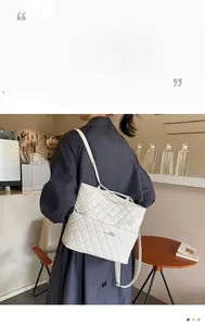 Detail of white quilted rhombic shoulder bag with silver plaque and adjustable strap