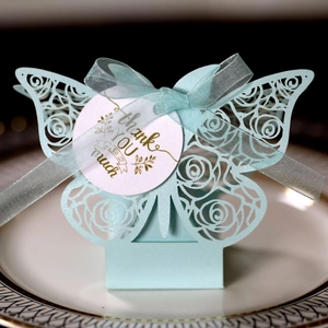 Detail of laser-cut light blue butterfly favor box with rose patterns and Thank You tag