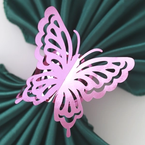 Detailed view of laser-cut pink butterfly napkin ring with pearlescent texture on green fabric