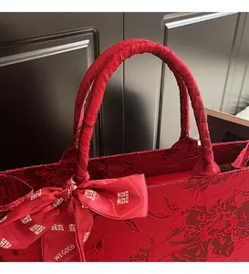 Close-up of red wedding tote bag with floral jacquard texture and Xi character bow
