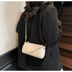 Creamy white cylinder shoulder bag in pebbled leather with gold hardware on model