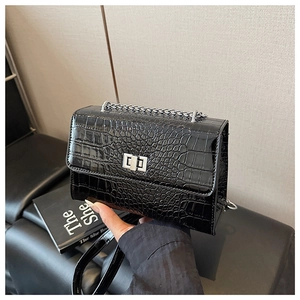 Detail of black crocodile texture bag with silver chain strap and metal swivel lock