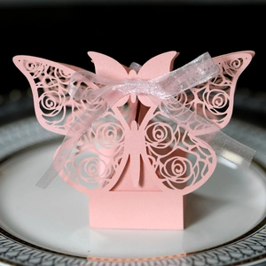 Detail of pink laser-cut butterfly gift box with rose patterns and white organza ribbon
