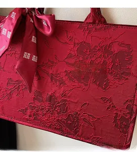 Detail of red wedding tote fabric featuring floral embroidery and silk ribbon with Xi symbol