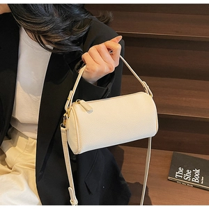 Detail of off-white lychee leather pillow bag with gold zippers in minimalist style