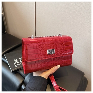 Detail of red crocodile texture crossbody bag with silver metal twist lock closure
