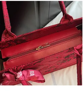 Close-up of the smooth golden metal zipper closure on the red jacquard wedding tote bag