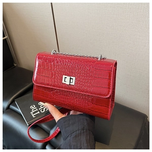 Close-up of a red crocodile pattern shoulder bag with a silver chain and metal twist lock