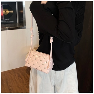 Detail of pink patent leather shell bag with quilted rhombic pattern and silver rivets