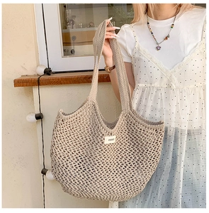 Détail du sac cabas en maille beige avec étiquette 'ouur' et large bandoulière tissée