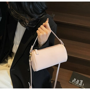 Close-up of pink cylinder shoulder bag with lychee pattern and gold zipper details