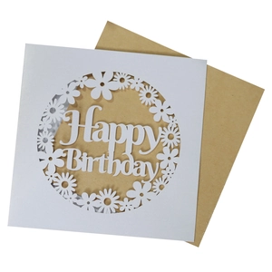 Close-up of laser-cut white Happy Birthday card with intricate floral patterns and kraft envelope