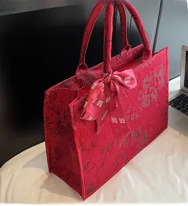 Detail of red jacquard tote bag featuring floral embossed fabric and bow ribbon