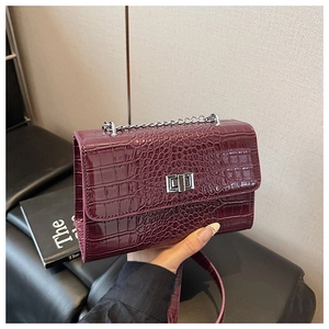Detail of burgundy crocodile pattern crossbody bag with silver rotating lock and chain