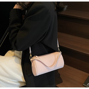 Detailed shot of blush pink litchi grain leather texture and gold hardware on crossbody bag