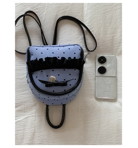 Détails d'un mini sac à dos à rayures cœurs, avec bordures en dentelle et nœud décoratif