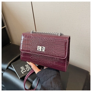 Detail of burgundy crocodile-textured bag featuring silver chain and square twist lock