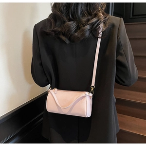 Pink lychee grain leather cylinder bag with gold hardware shown on a model's back