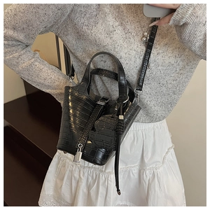 Detail of black faux crocodile leather mini bucket bag with gold lock and charm