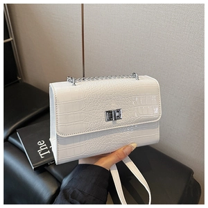 Detail of white crocodile embossed square bag with silver chain strap and metal lock buckle