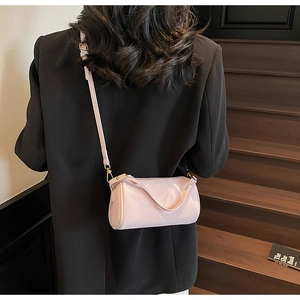 Detailed view of light pink pebble leather cylindrical crossbody bag with gold hardware
