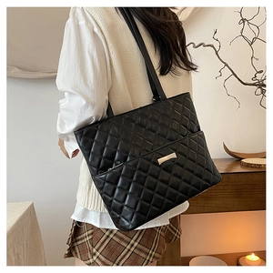 Chic black quilted tote bag with metallic logo shown in a cozy indoor lifestyle setting