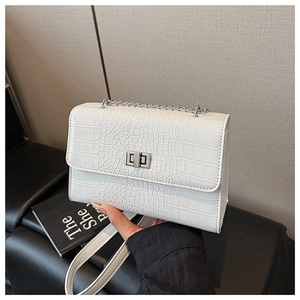 Detailed macro view of white crocodile pattern texture and silver buckle on shoulder bag