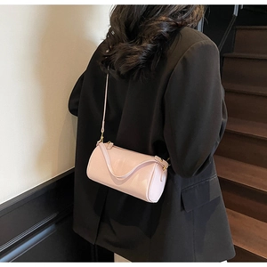 Pink cylinder crossbody bag with lychee leather texture and golden hardware details