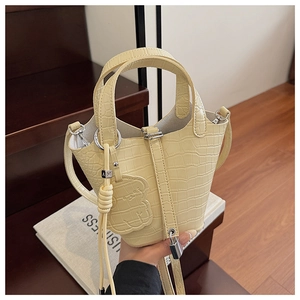 Close-up of cream yellow crocodile embossed mini bucket bag with bear charm and strap