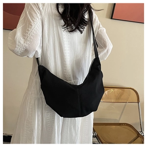 Detail of black corduroy crescent bag showing textured fabric and adjustable strap