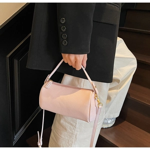Detail of light pink lychee texture leather cylinder bag with gold-tone metal hardware
