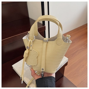 Detail of yellow crocodile embossed leather bucket bag with silver padlock and bear charm