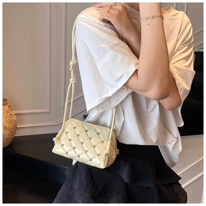 Detail of cream yellow crossbody bag with diamond quilting and sparkling rhinestones
