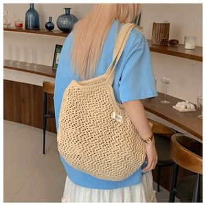 Vue détaillée du sac bandoulière en maille crochet crème avec étiquette de marque