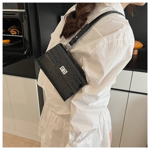 Detail of black crocodile pattern shoulder bag with silver lock on modern kitchen background
