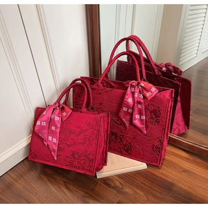 Macro shot of red jacquard wedding tote bags with floral texture and silk ribbons