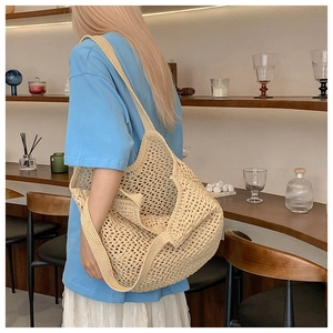 Gros plan détaillé du motif ajouré en crochet beige sur un grand sac en paille tressée