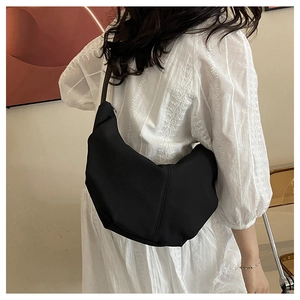 Close-up of minimalist black hobo bag with smooth fabric texture on model's shoulder