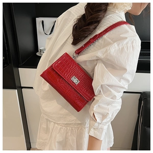 Detailed view of red crocodile pattern square shoulder bag with metal lock and chain strap