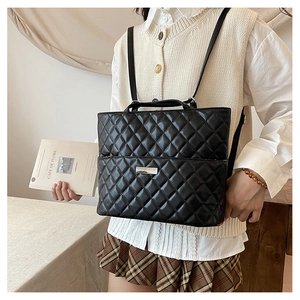 Detail of black quilted faux leather backpack with silver logo and thin straps